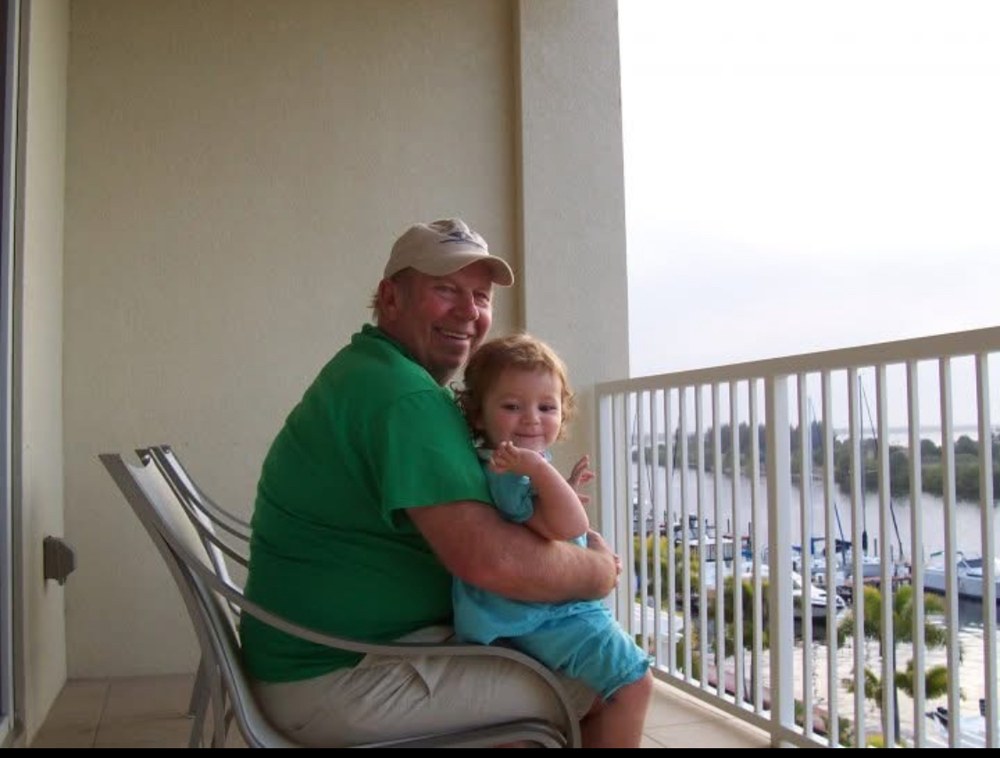A young Samantha sitting with her grandfather, Ron Parnell.