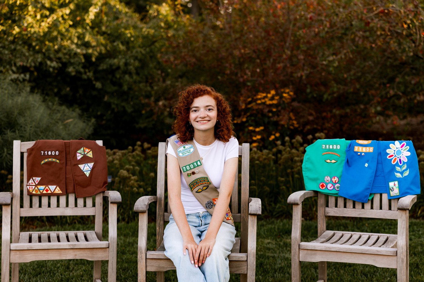 Samantha in her Girl Scout sash, seated beside her earlier Girl Scout uniforms.